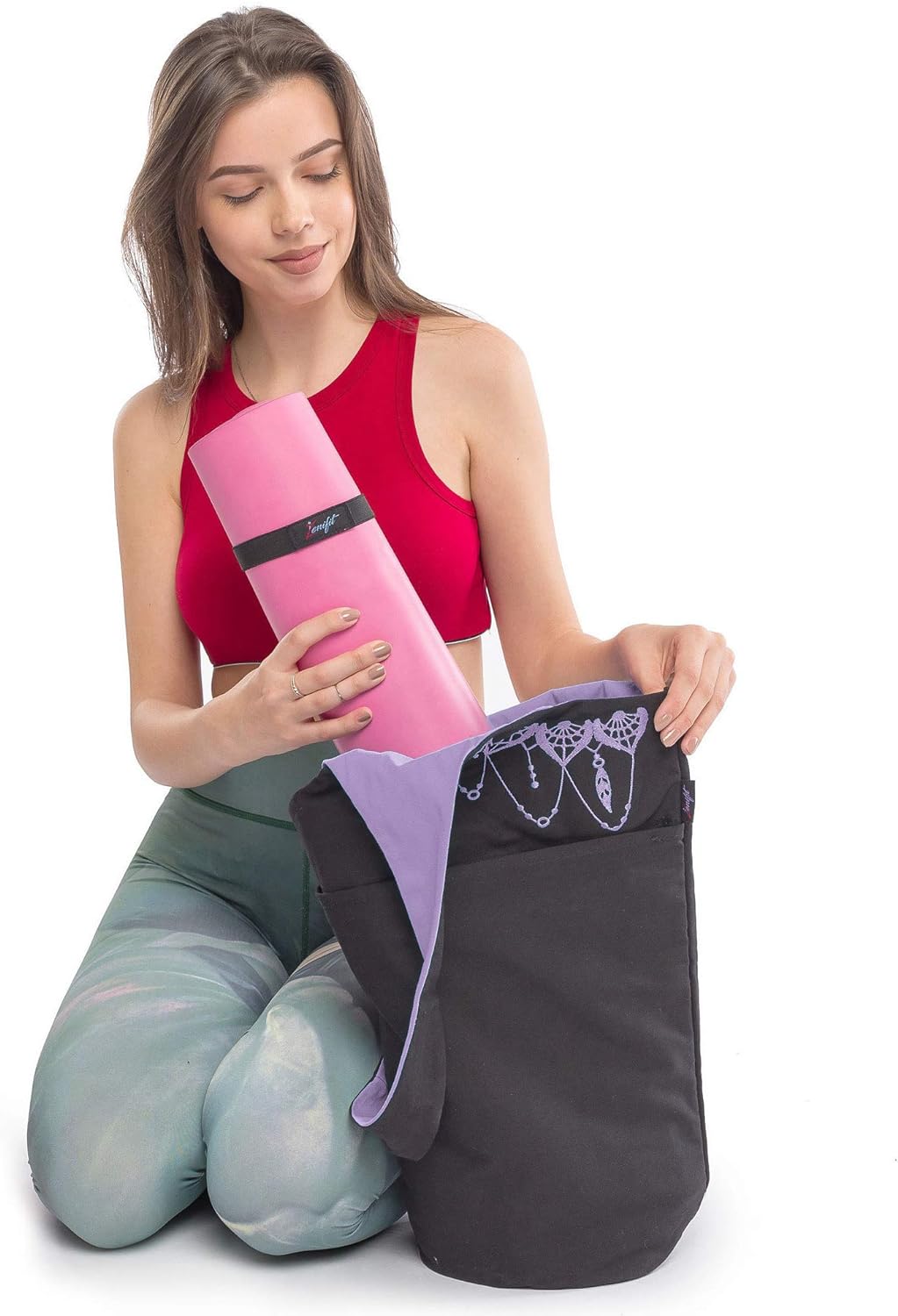 women putting yoga mat in th yoga bag on her knees
